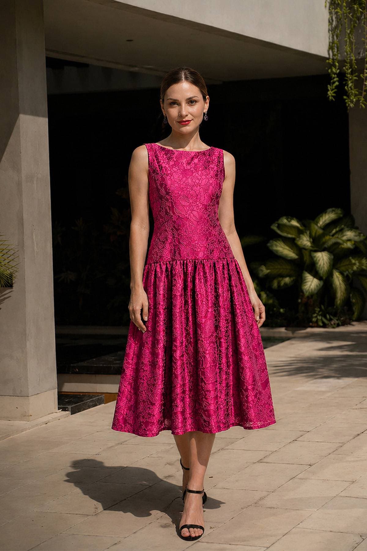 A woman in a sleeveless pink lace dress stands confidently on a tiled surface.