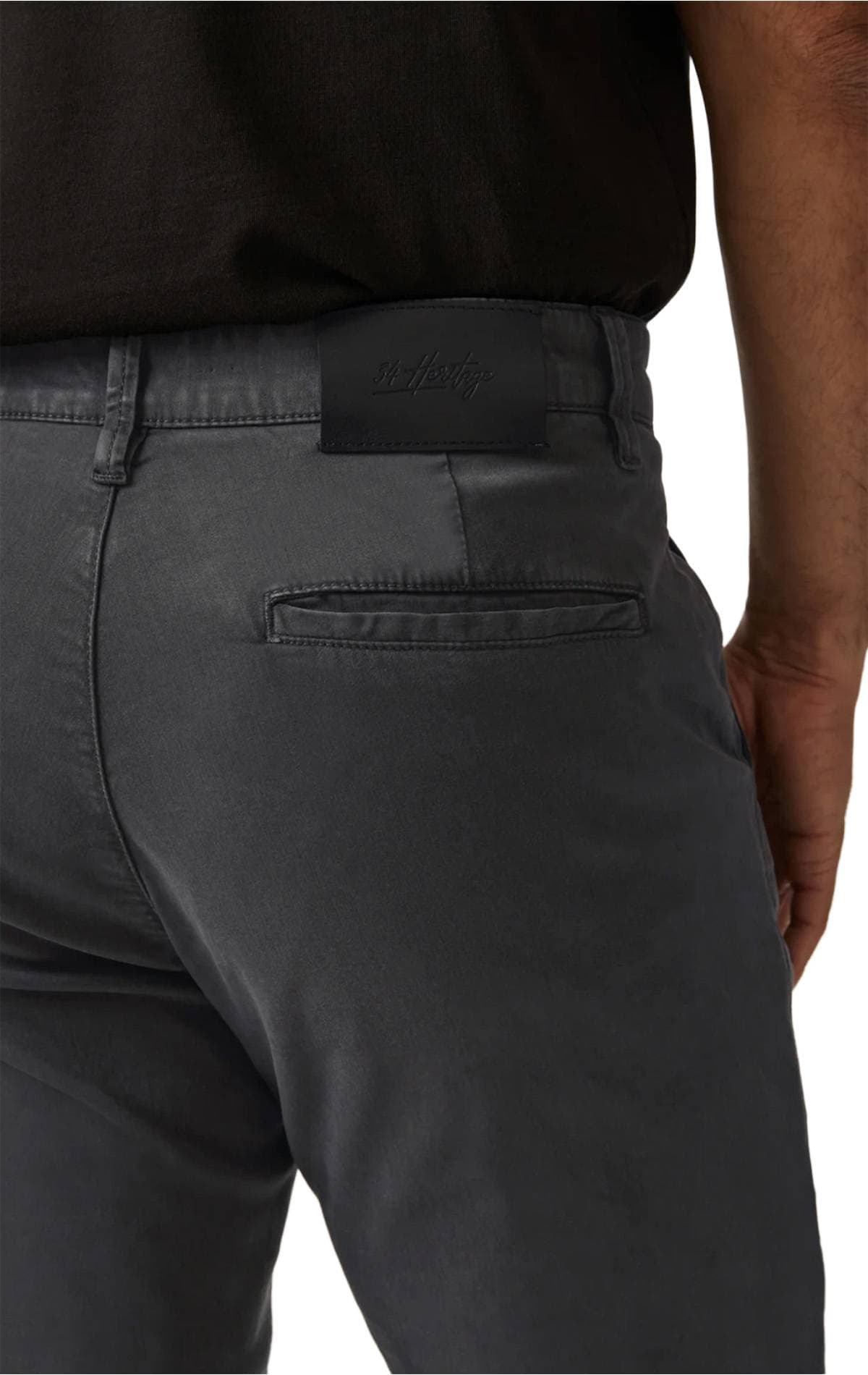 A person wearing dark gray pants with a black belt and tucked-in black shirt, showing the back pocket and waistband.