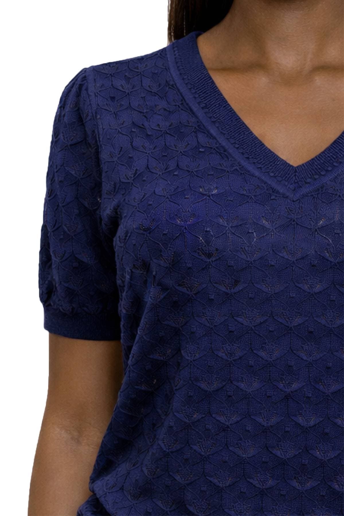 A person wearing a blue textured V-neck top with short sleeves.