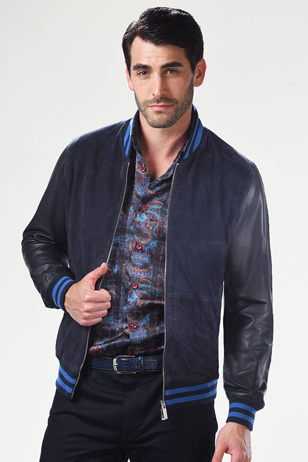 Male wearing suede dark blue jacket on top of colorful long-sleeve satin shirt in blue, red, and brown tones.